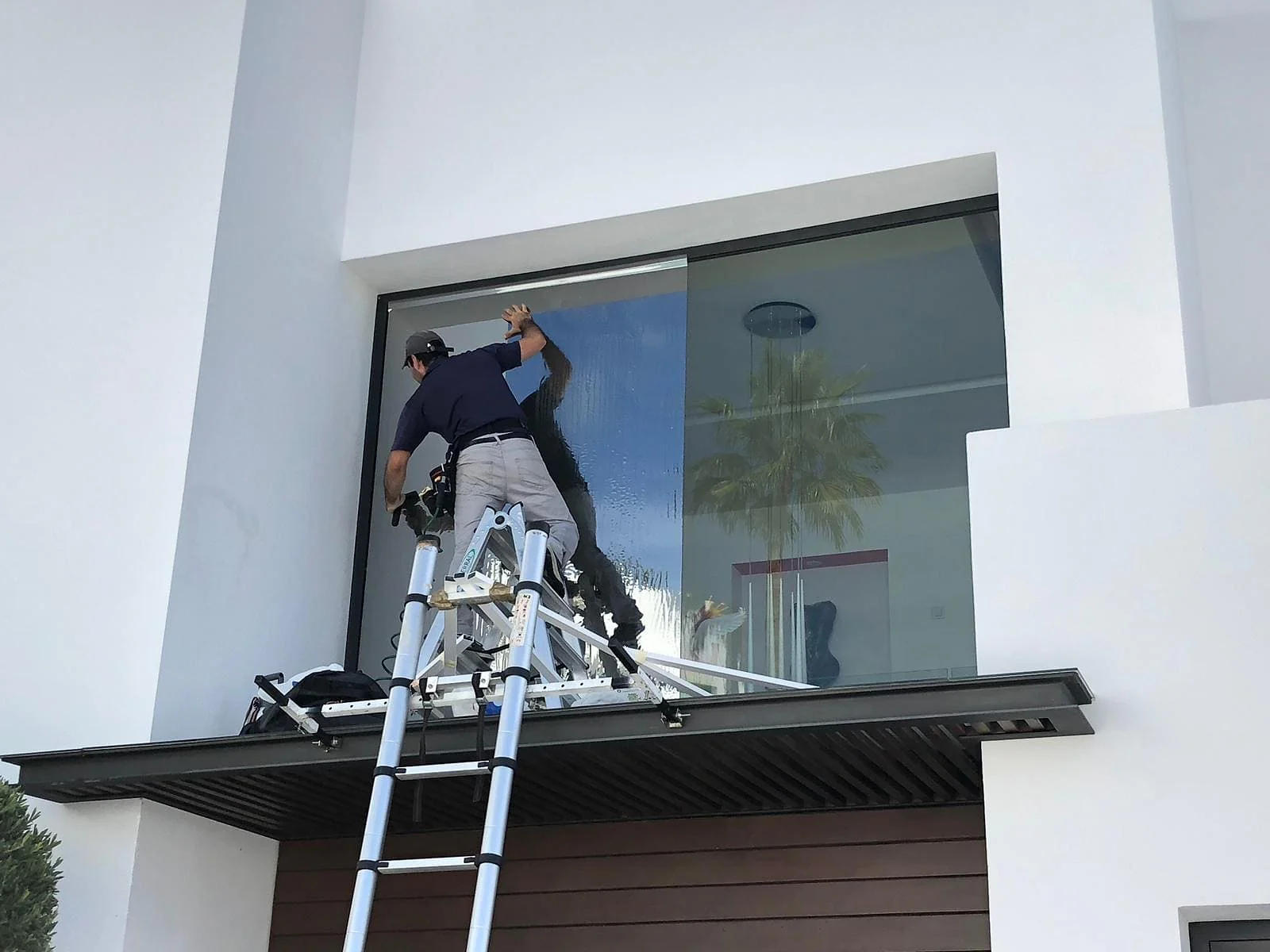 Lumina Films installer applying window film to villa glazing